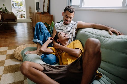 Happy gay couple relaxing together on the couch in modern apartment