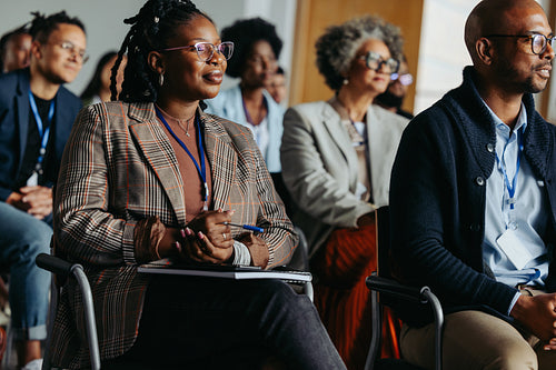 Diverse business audience attending a conference presentation, colleagues sitting and taking notes