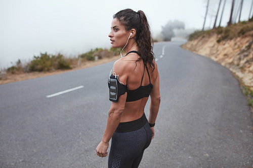 Fit young woman in sportswear standing on a country road