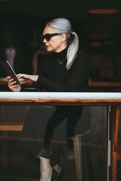 Senior businesswoman relaxing at cafe using digital tablet