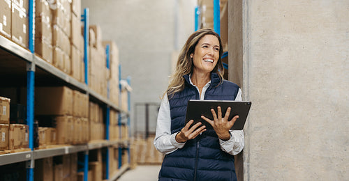 Happy young woman holding a digital tablet in a warehouse