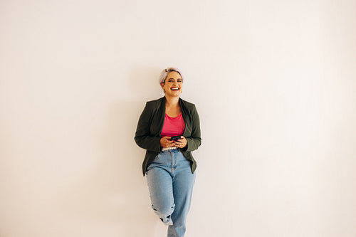 Happy young businesswoman holding a smartphone in an office
