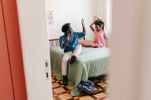 Happy daughter pillow fighting her dad at home