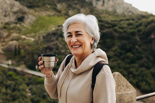 Mature woman having a hot drink on a hilltop