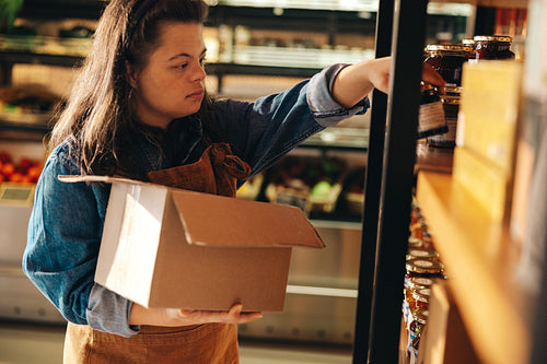 Supermarket employee with Down syndrome restocking food products