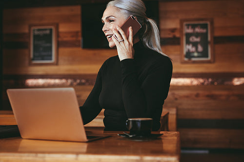 Senior businesswoman having a phone call with client at cafe