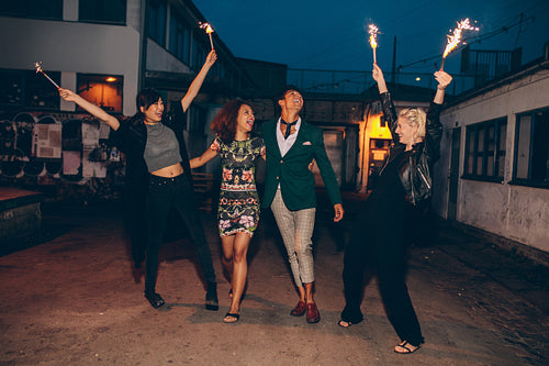 Group of friends enjoying with sparklers on road