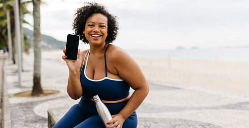 Healthy young woman recommending a fitness app for beach workouts