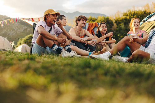 Happy gathering of youthful individuals at a festival camp, engaging in lively conversations, sipping beer, and creating a fun atmosphere