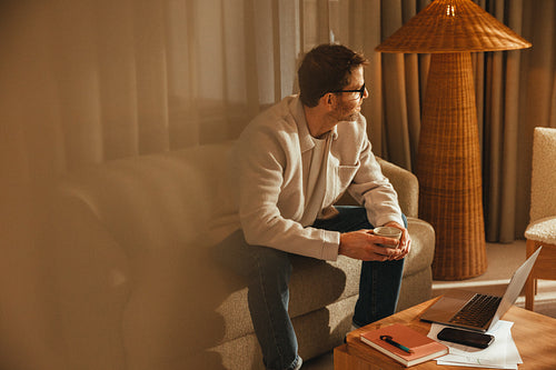 Business owner pauses from work beside a laptop and phone in an office workspace