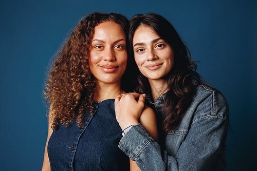 The pair of women stands together in a studio portrait about friendship and support