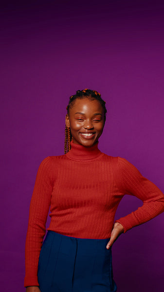 Young woman with braids and colorful turtleneck poses confidently