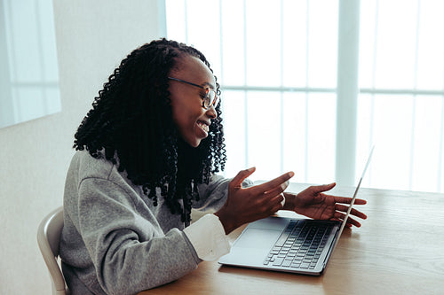 Friendly woman taking a video call on her laptop while gesturing passionately