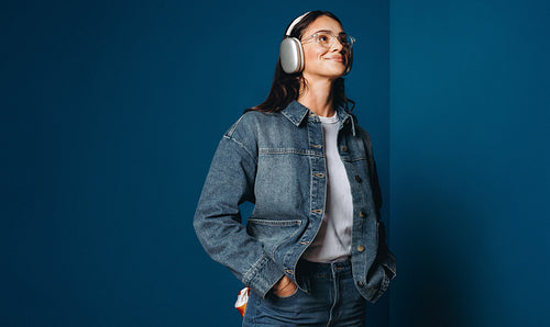Headphones frame a woman in a vibrant monochromatic color blocking setting with a relaxed smile