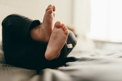 Baby lying on bed moving his feet