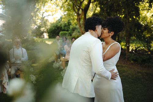Bride and groom share a kiss during a beautiful outdoor wedding ceremony