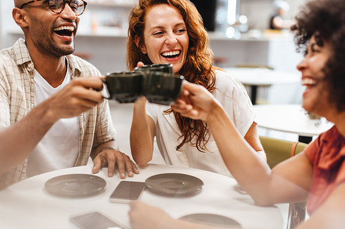 Group of friends making a toast in a coffee shop, celebrating friendship