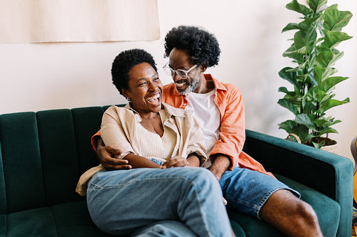 Husband and wife laughing and having a good time together on a couch