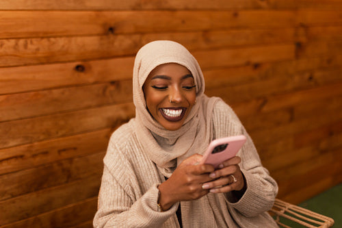 Excited muslim woman sending a text message in a restaurant