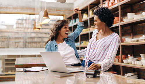 Happy female ceramists celebrating their success in their shop