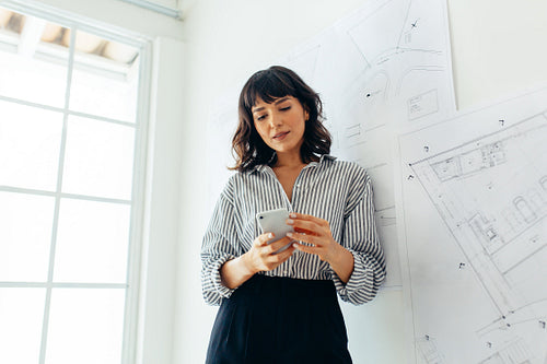 Female architect in office using mobile phone