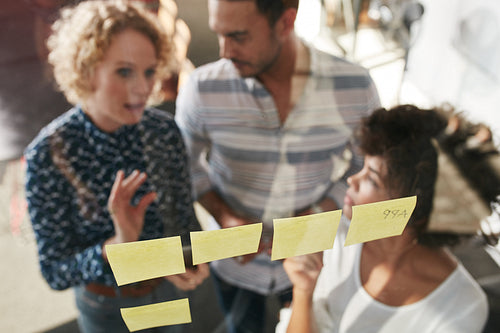 Three business people having a meeting at sticky note wall