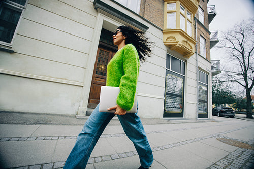 Woman walking in the city with laptop for work and commuting