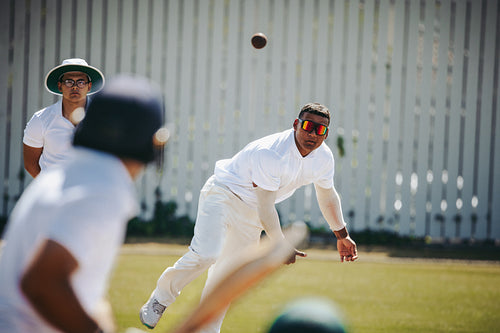 Cricket bowler in action during a competitive match on a sunny day