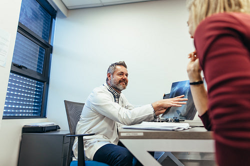 Medicine practitioner with x-ray talking to a woman
