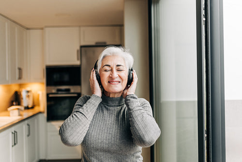 Senior woman enjoying listening to music on wireless headphones