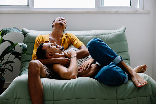 Happy gay couple relaxing on a cozy couch at home