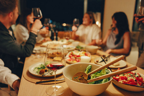 Friends enjoying drinks and salad at a cozy dinner table gathering