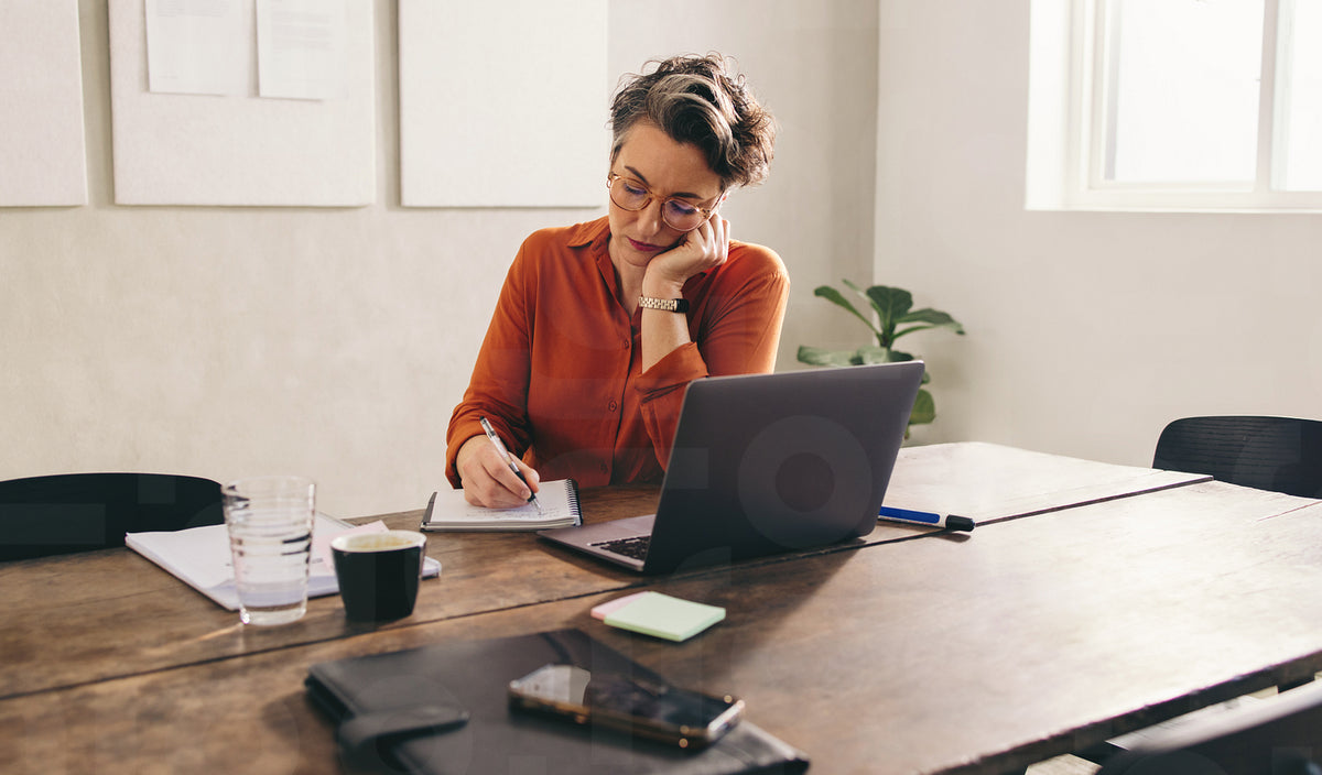 Mature businesswoman writing in her diary in an office – Jacob Lund ...
