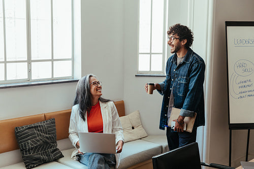 Senior manager and colleague having a casual conversation during a workshop