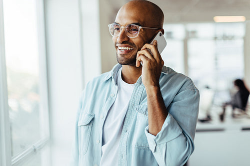 Young business man talking on a mobile phone in his workplace