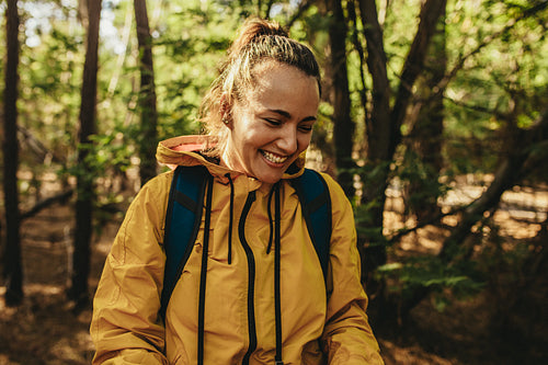 Woman with backpack standing in forest and smiling