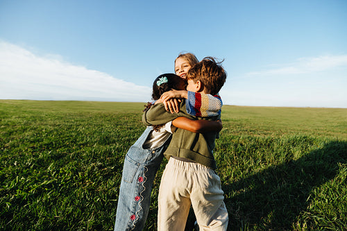 Young children embracing in a grassy field