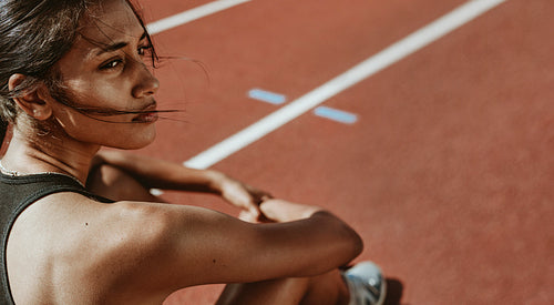 Fit woman after run sitting on race track