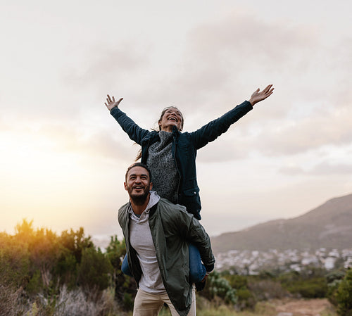 Young man piggybacking his girlfriend in countryside