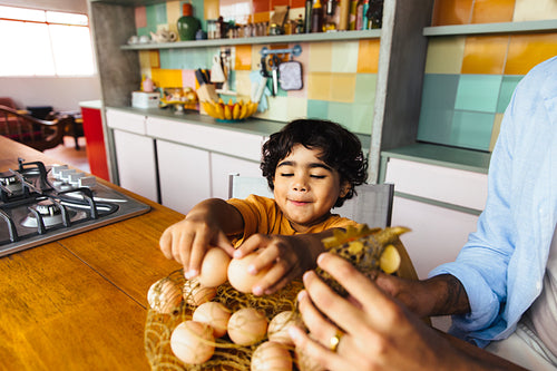 Child enjoying a kitchen moment with a family member handling fresh eggs
