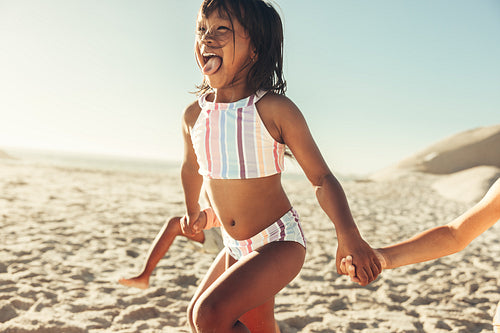 Fun-loving little girl running with her friends at the beach