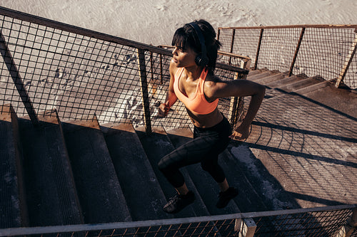 Woman running up the stairway along the beach