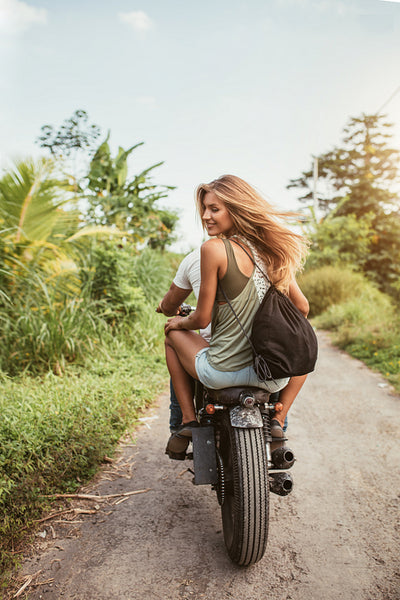 Young couple riding motorbike on dirt road