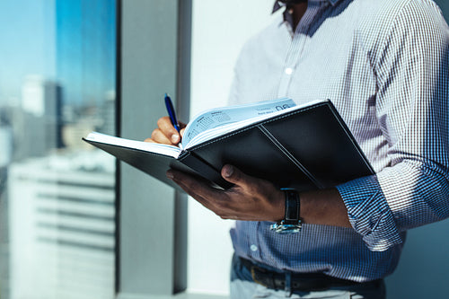 Closeup of a business investor writing in diary.