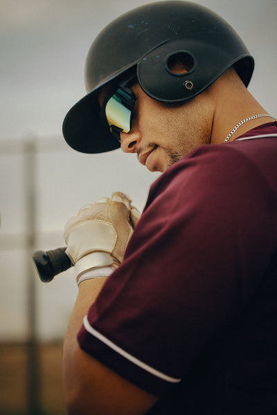 Male baseball batter wearing sunglasses and a helmet prepares to bat during a game,