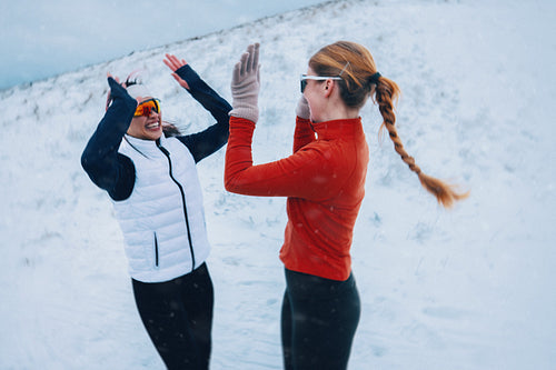 Women embrace fitness and friendship with a high five during winter run