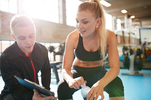Personal trainer helping young woman with her fitness plan