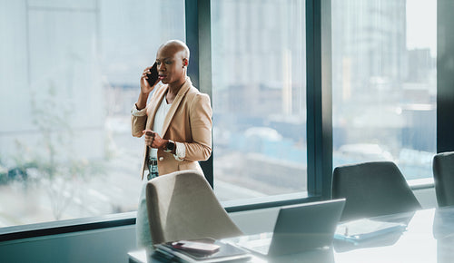 Bald businesswoman discussing company matters on smartphone in office