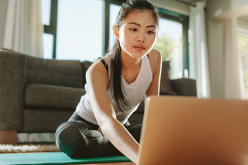 Woman looking at fitness videos on laptop at home