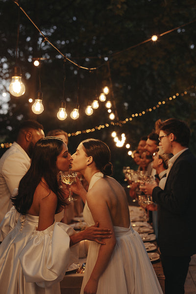 Two women sharing a kiss during their outdoor wedding celebration